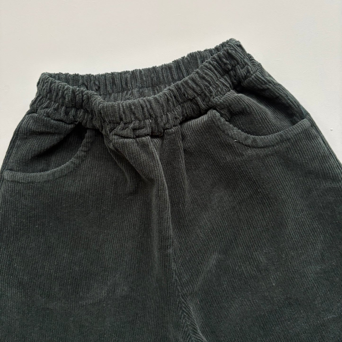 elastic waistband and front pockets on green corduroy trousers