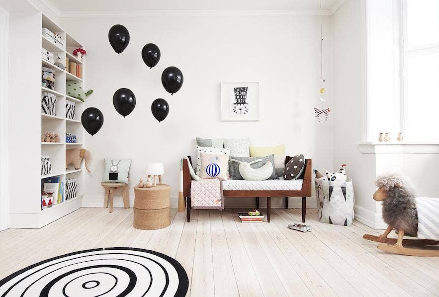 Children's room with black balloons on the wall, a bed, and various decor items.